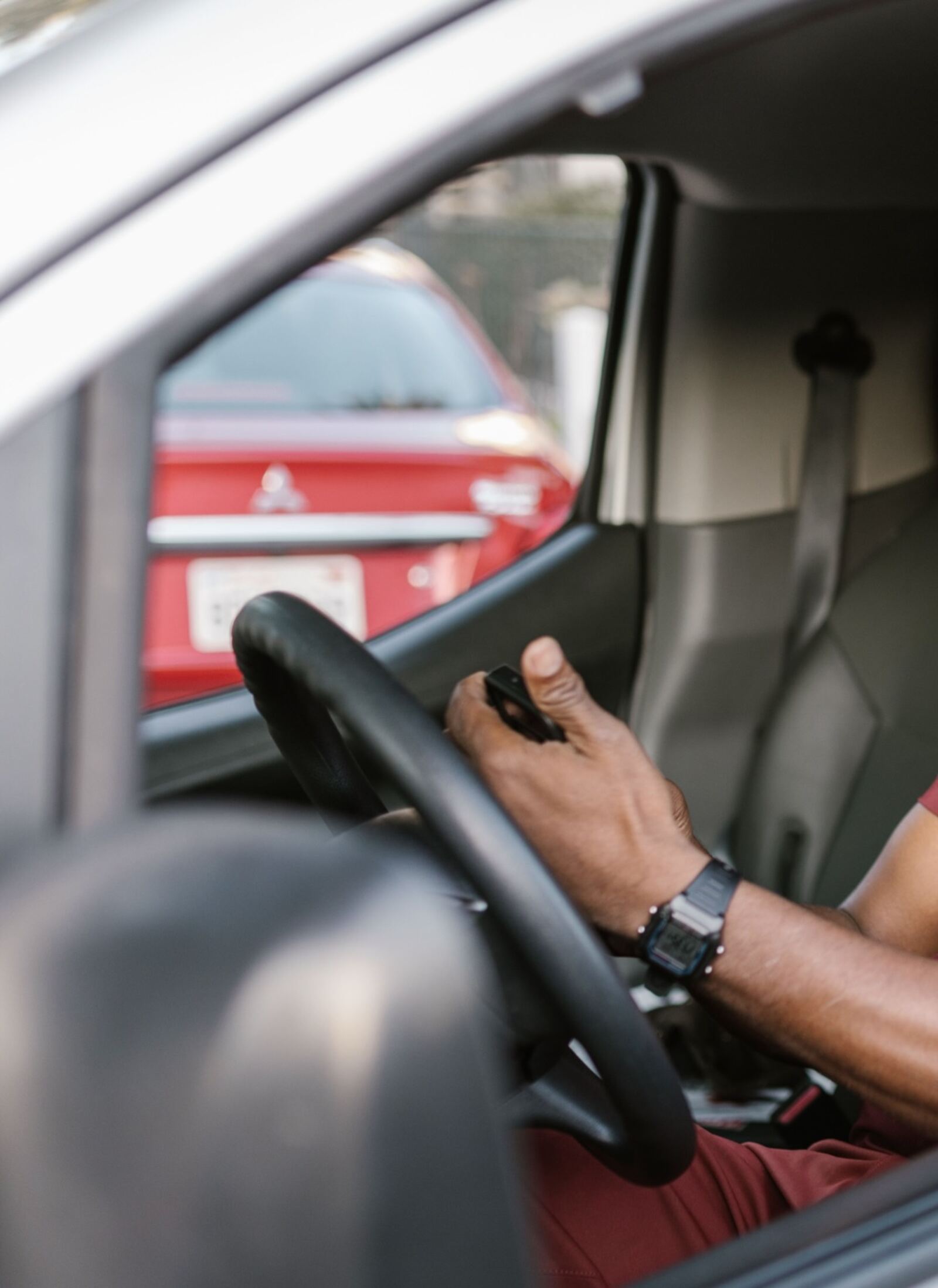 Vu par la fenêtre ouverte d'une camionnette, un artisan au volant tient son téléphone en main.